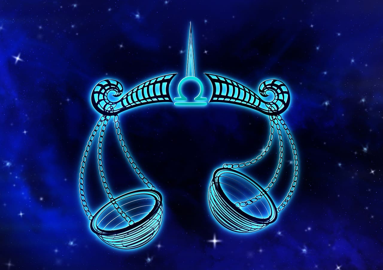 A glowing Libra zodiac symbol with scales, set against a starry, blue galaxy background, complements the elegance of Cancer zodiac outfits.